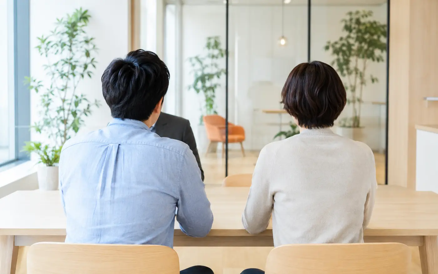 明るい相談室で並んで話を聞く2人の後ろ姿(架空・イメージ)